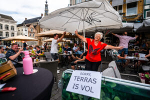 Een foto van een dansende dame op een terras in Den Bosch op 1 juni, de dag dat de horeca weer open mocht.
