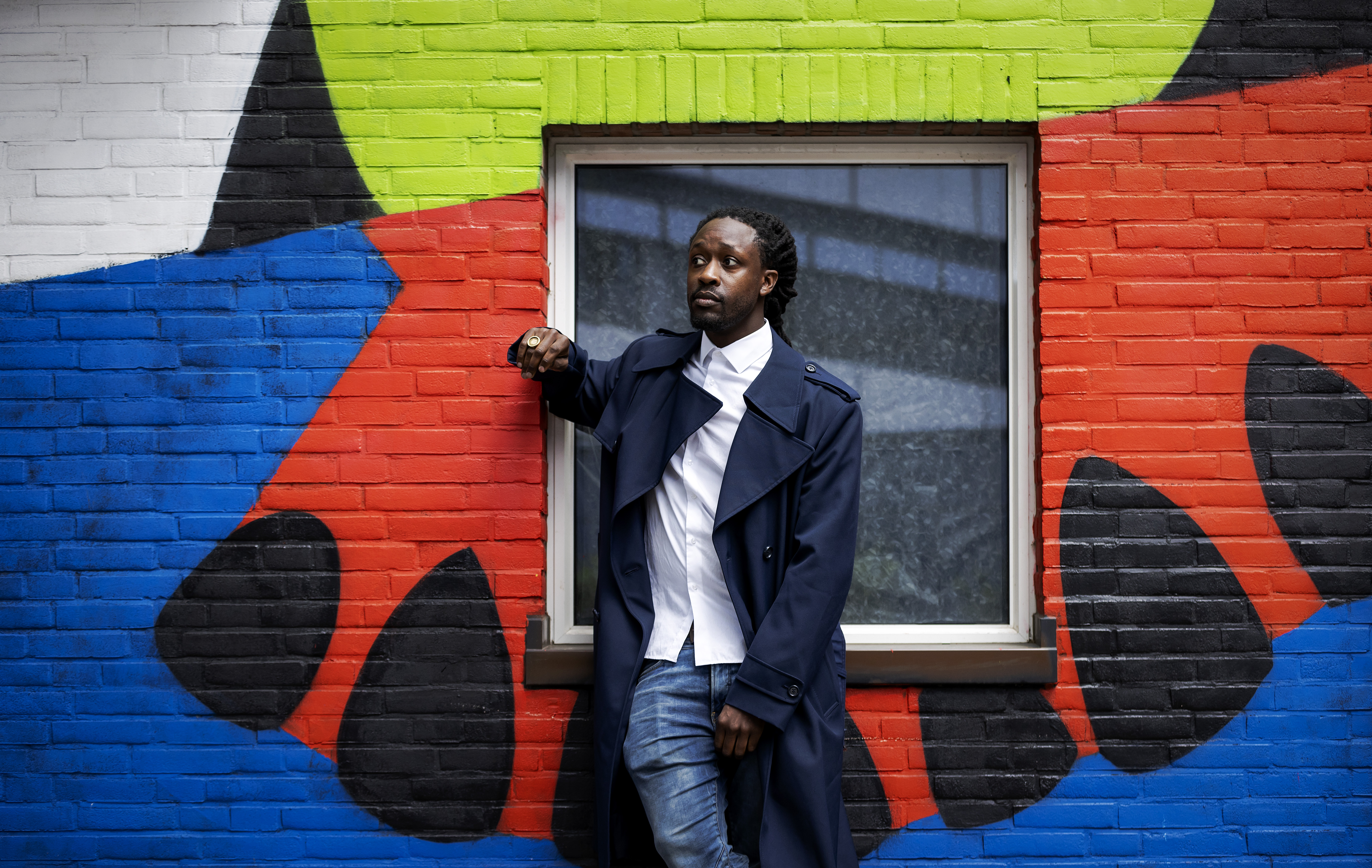 Een foto van rapper Akwasi voor een kleurige muur