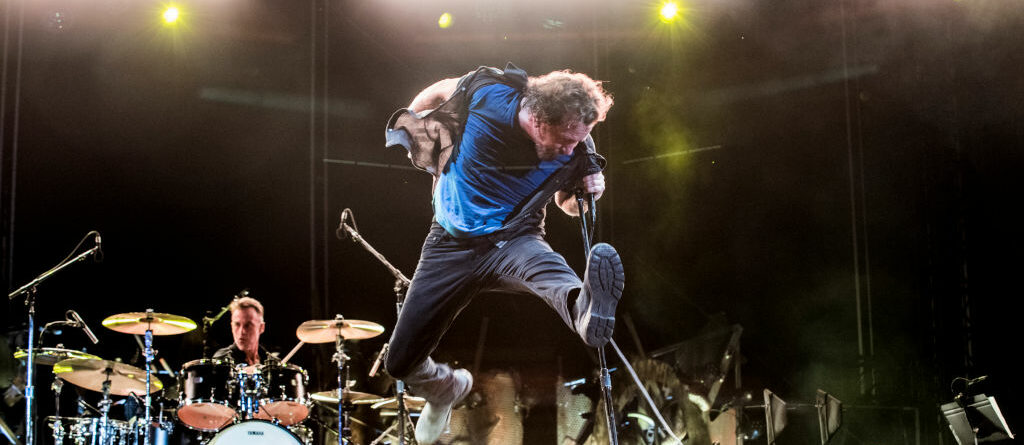 Een foto van een springende Eddie Vedder tijdens een liveconcert