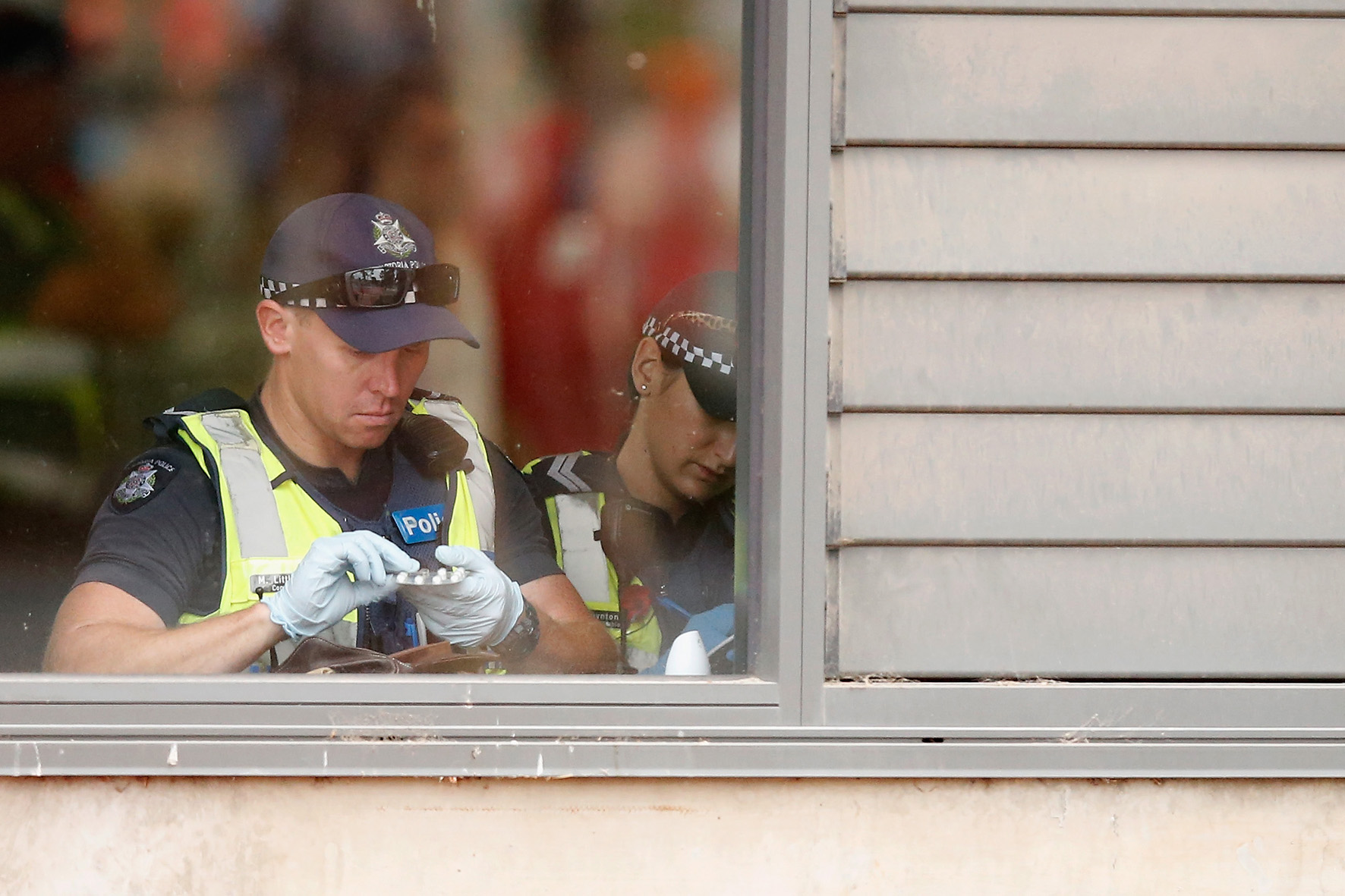 Op deze foto zie je politie in Australie tijdens een festival iemands pillen uit een tas controleren.