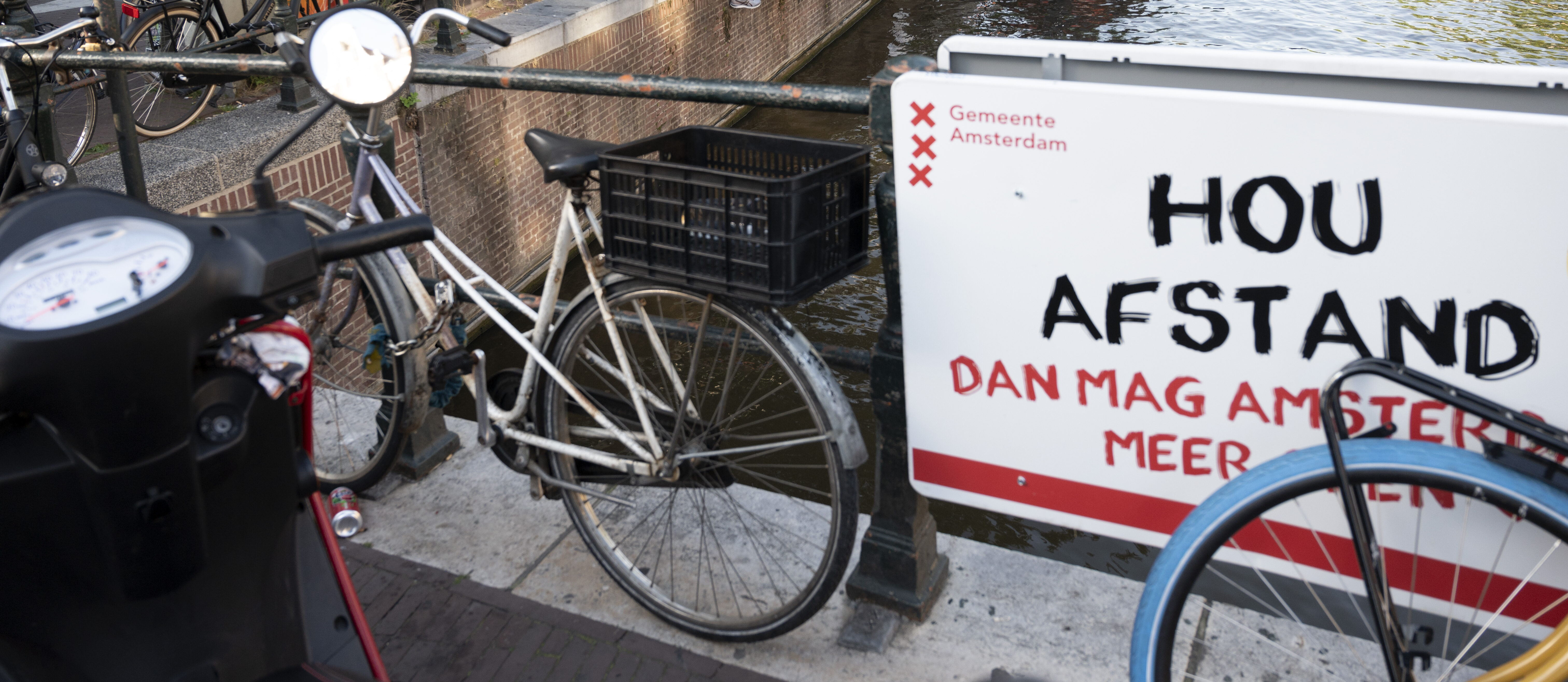 Een foto van een bord met de tekst houd afstand aan een Amsterdamse brug