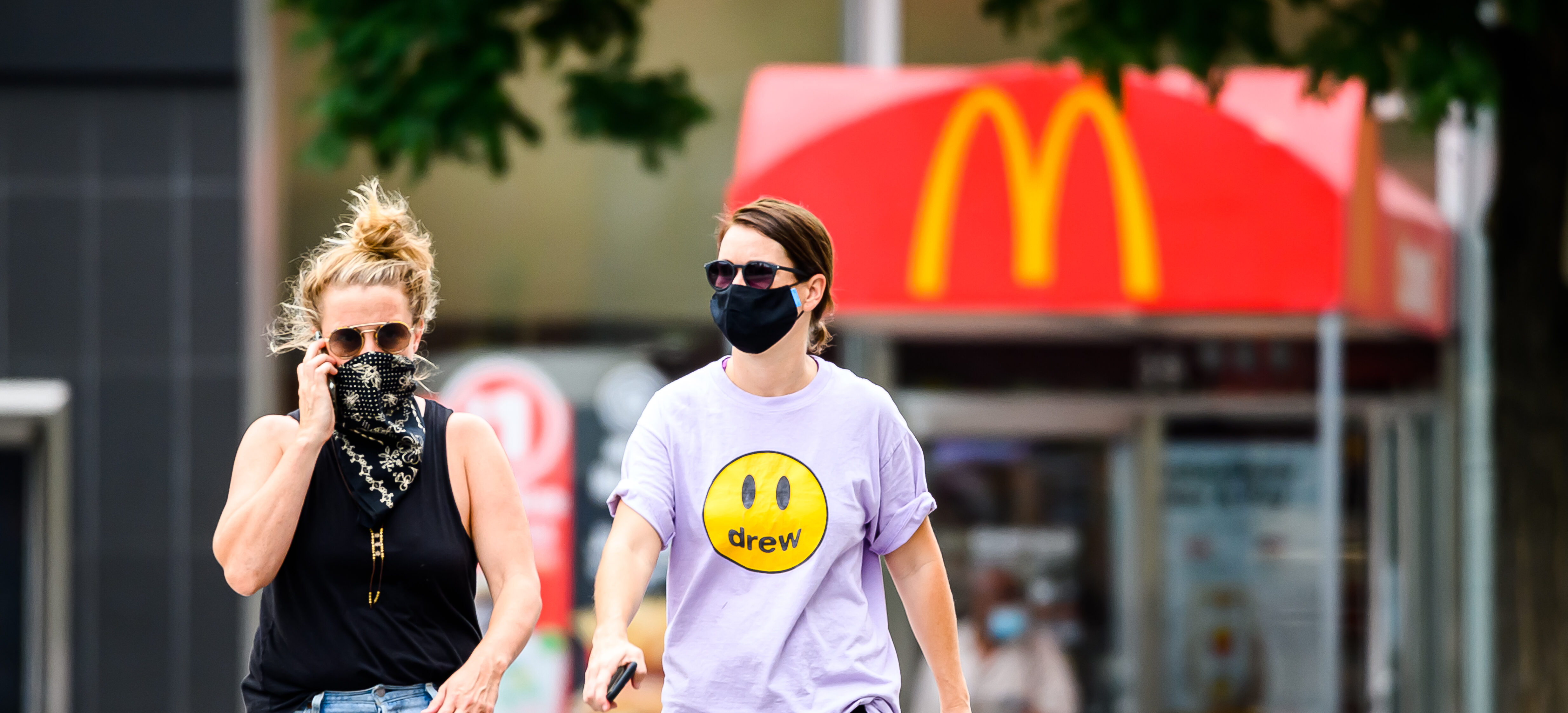 Een foto van twee dames met een mondkapje voor een McDonald's-vestiging