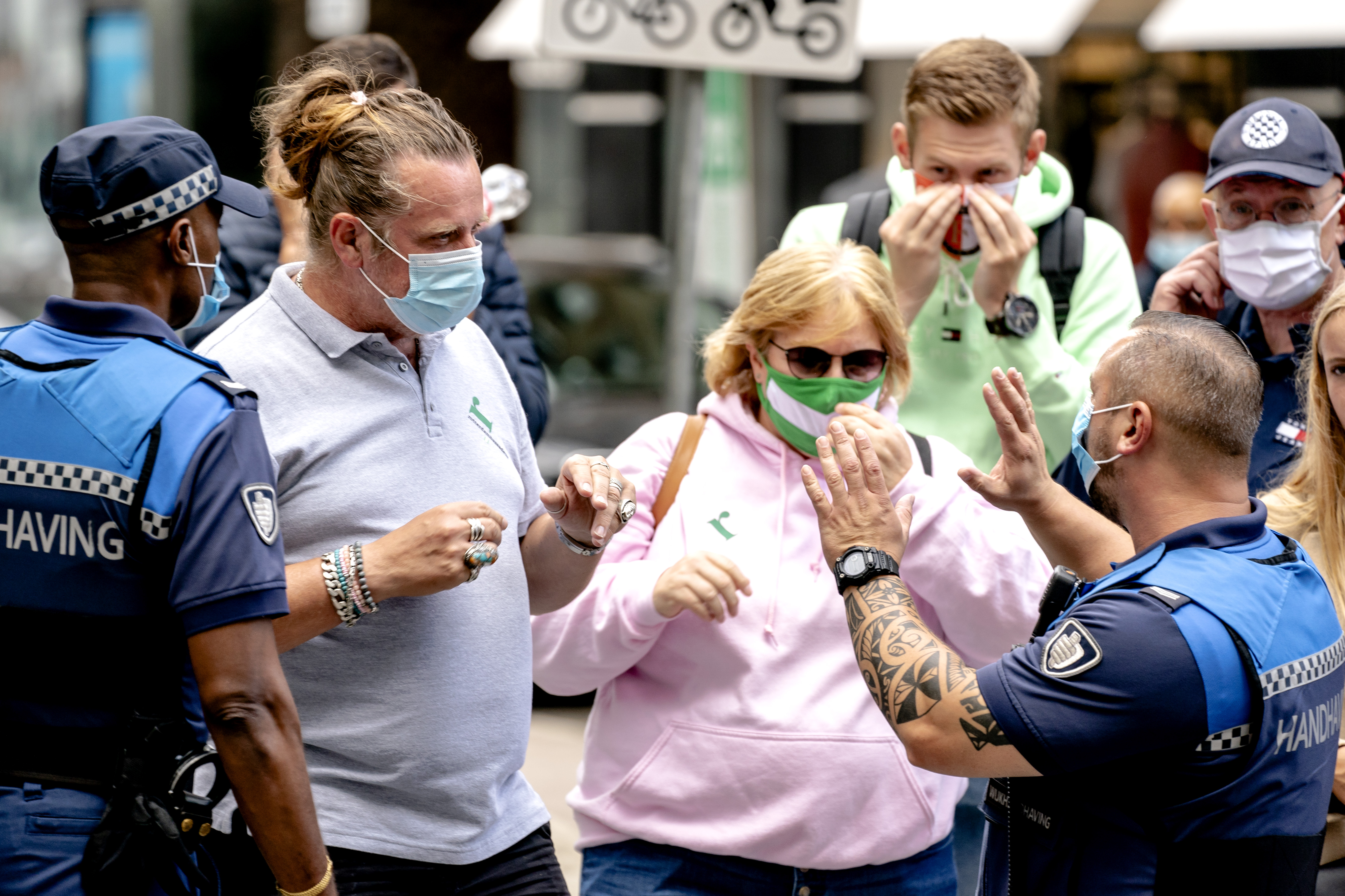 Een foto van handhavers die in Rotterdam checken of verplichte mondkapjes worden gedragen.
