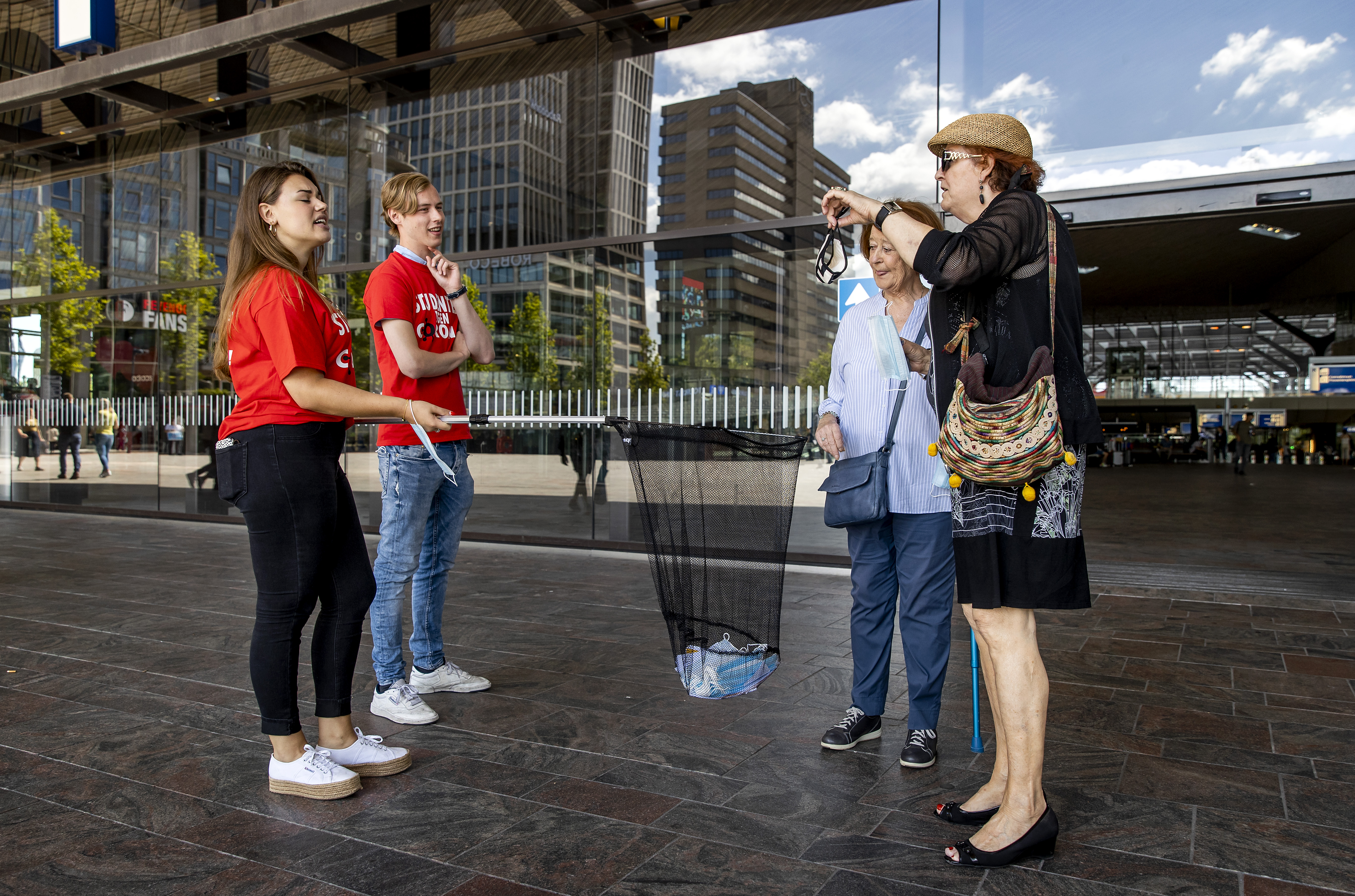 Een foto van studenten in Rotterdam die anderen wijzen op het afstand houden
