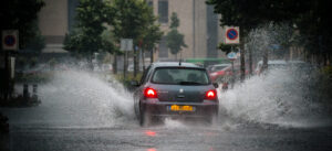 Een foto van een auto die door enorme plassen water rijdt neerslag
