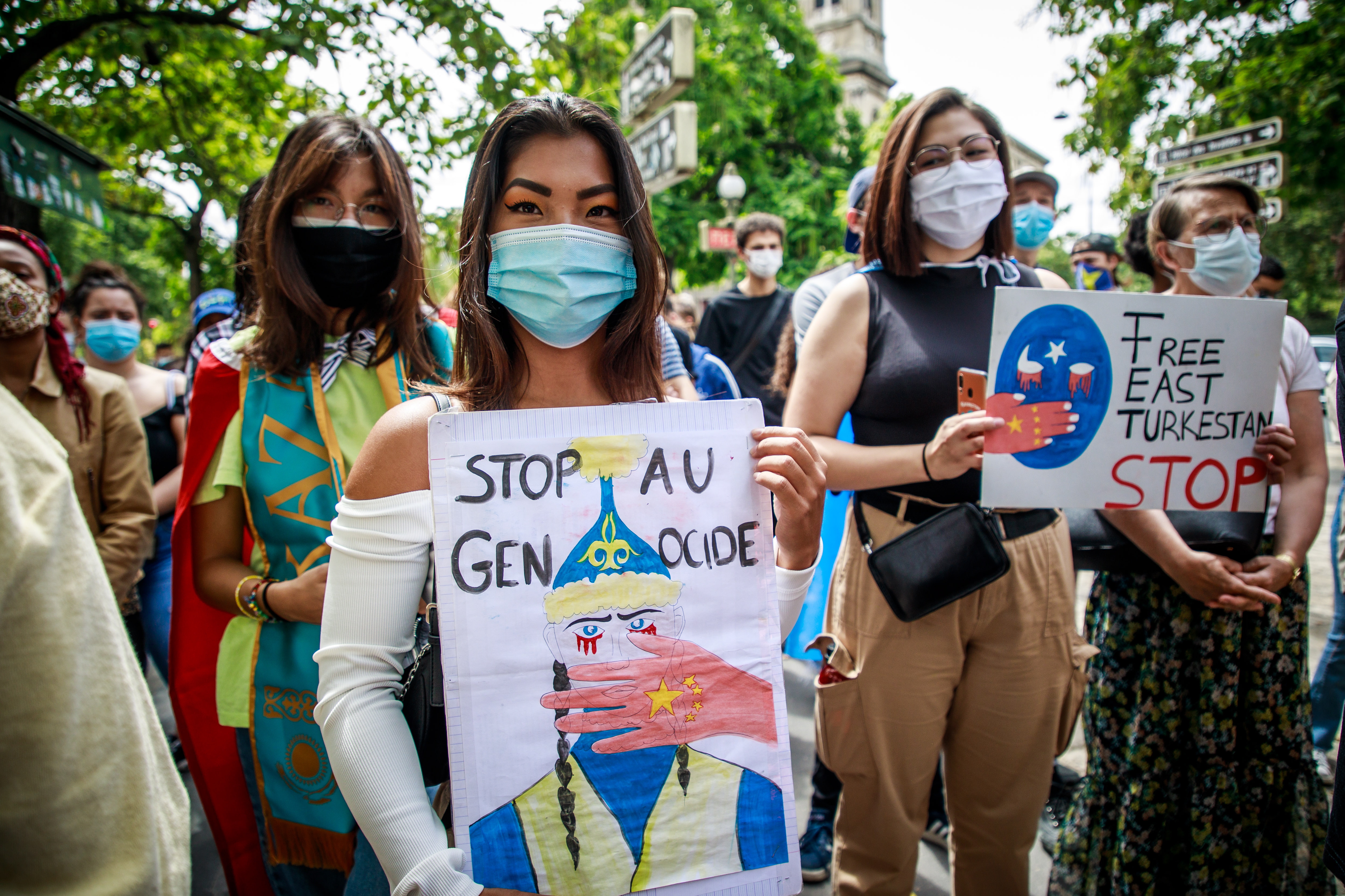 Op deze foto zijn mensen te zien tijdens een demonstratie voor de Oeigoeren in China. Ze houden borden vast met 'stop AU genocide'.