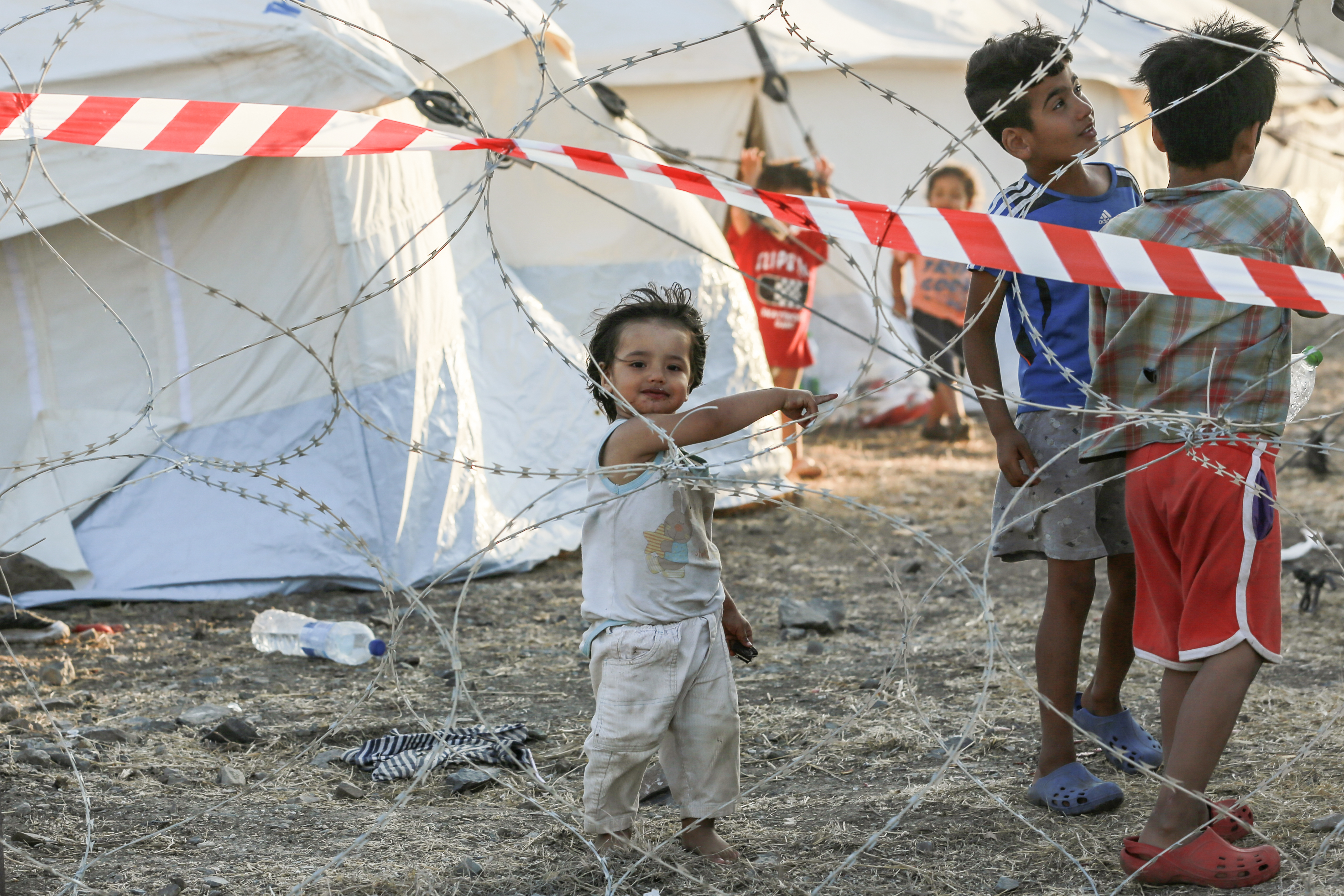 Op deze foto zijn drie kinderen in een vluchtelingenkamp te zien.