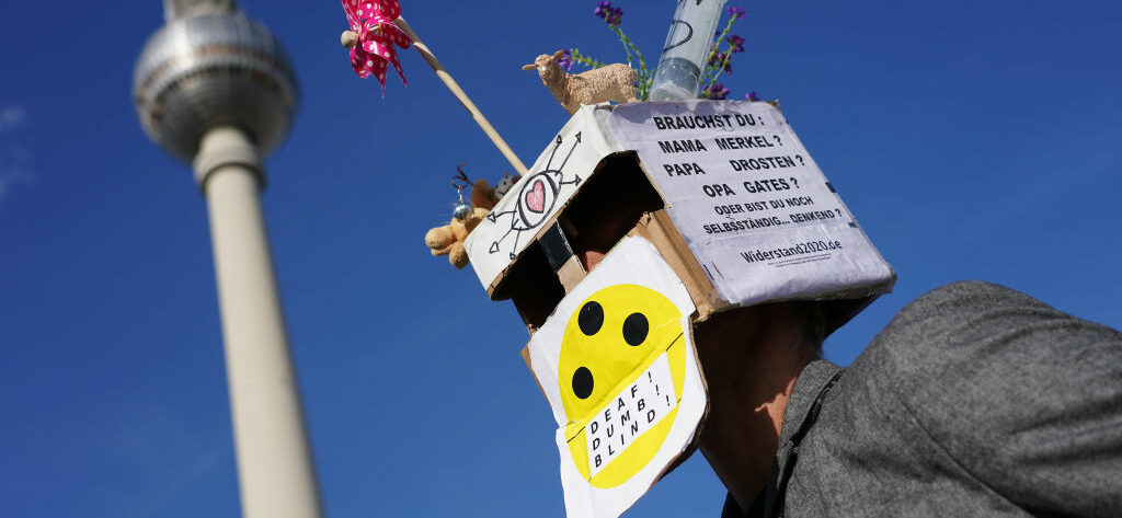 Een foto van een man met een gek masker die in Berlijn protesteert tegen de coronamaatregelen