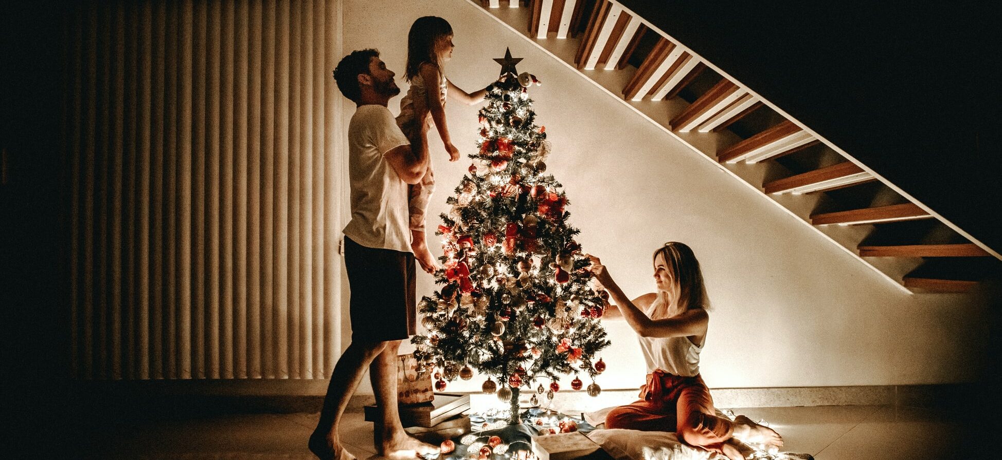 Twee mensen met hun kind bij de kerstboom.
