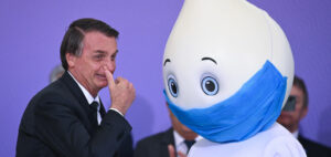 Een foto van de president van Brazilië met een mascotte voor het coronavaccin