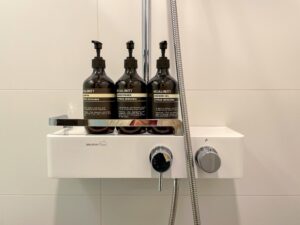 Drie flessen shampoo, conditioner en douchegel in een hotel.
