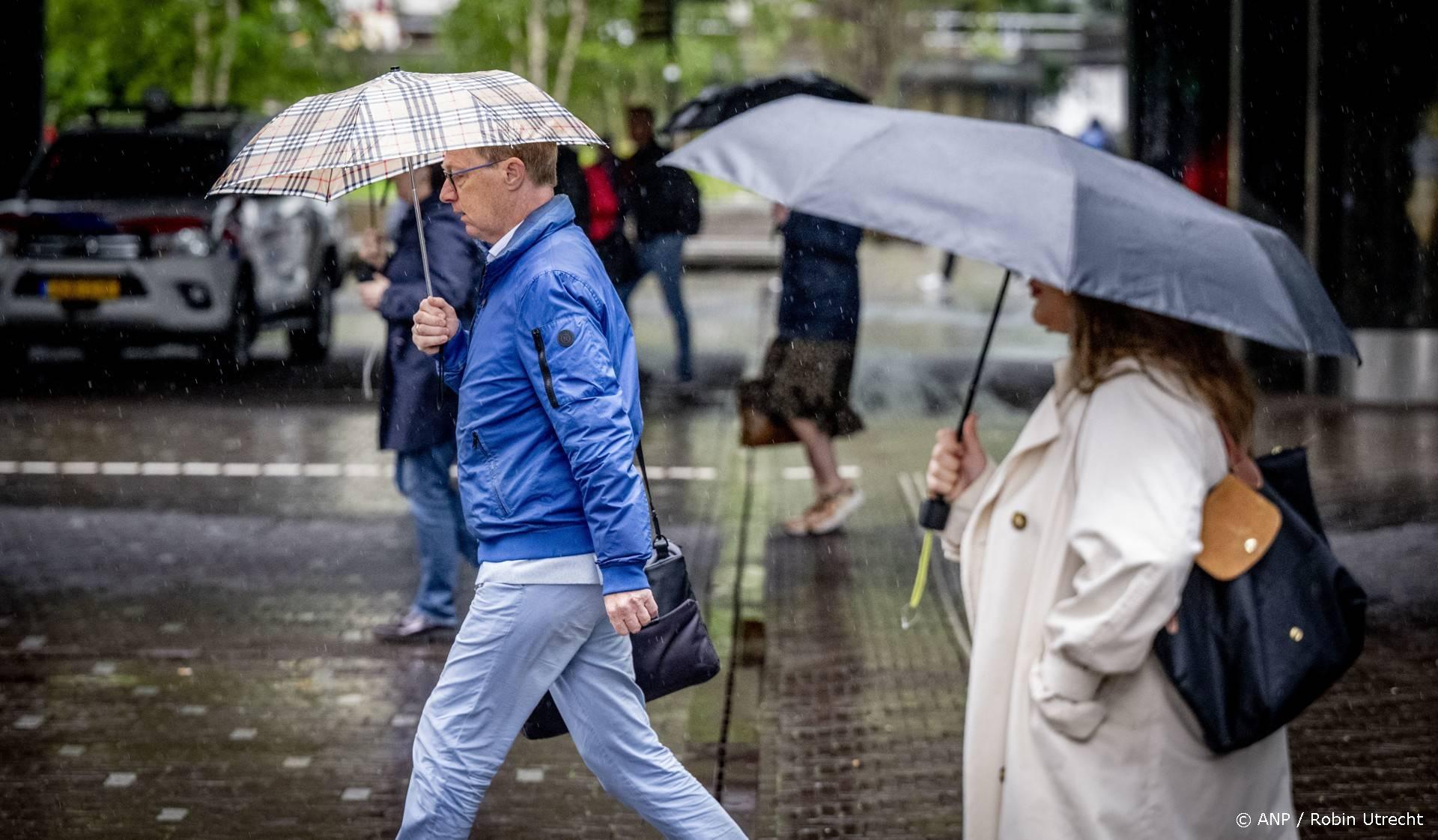 DEN HAAG - Mensen op straat trotseren regen en windstoten. Weerinstituut KNMI heeft voor delen van het land code geel afgegeven. ANP ROBIN UTRECHT